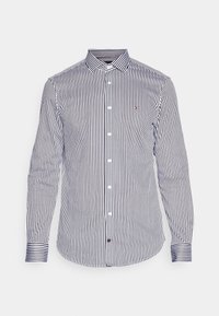 Camicia a maniche lunghe con righe verticali blu navy e bianche, colletto button-down, bottoni bianchi e piccolo logo sul petto.