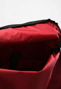 Interior rojo de una bolsa, con un cierre negro a lo largo del borde superior. La tela parece suave y duradera. Incluye un separador horizontal en el interior.