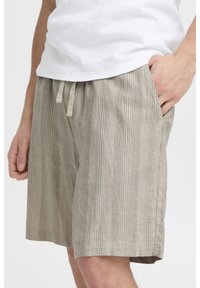 Beige gestreifte Shorts aus leichtem Stoff, mit elastischem Bund, Kordelzug und Seitentaschen.