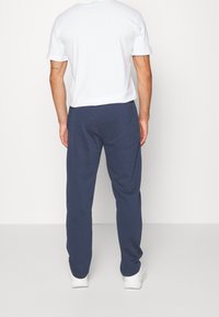 Witte T-shirt met korte mouwen en marineblauwe trainingsbroek, gemaakt van zachte stof. Het T-shirt heeft een ronde hals, de trainingsbroek heeft een elastische tailleband.