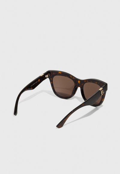 Lunettes de soleil écaille de tortue avec un design en forme d'œil de chat, des verres marron et des accents dorés sur les branches, présentant une finition brillante et une texture lisse.