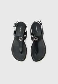 Μαύρα δερμάτινα σανδάλια-φλιπ φλοπ με λουράκι στο ανάμεσα στα δάχτυλα, που διαθέτουν κυκλικό ασημένιο λογότυπο MK και ρυθμιζόμενο λουράκι στον αστράγαλο.