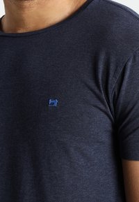 Navy blue T-shirt made of soft cotton, featuring a round neckline and a small blue sewing machine logo on the left chest.
