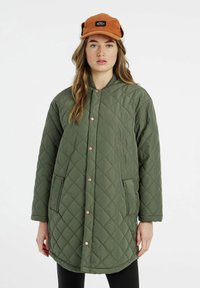 Prešívaná zelená bunda s okrúhlym výstrihom, zapínaním na cvoky, dvoma zipsovými vreckami a mäkkou textúrou.