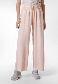 Roze wijde broeken met een elastische tailleband, trekkoord en twee voorzakken. Lichtgewicht stof met textuur.