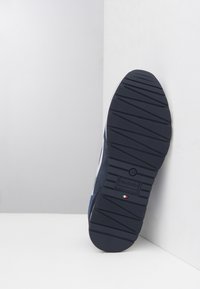 Sole in blu navy con gomma testurizzata per una buona presa, caratterizzata da un accento bianco e un dettaglio della bandiera italiana. Profilo piatto con punta arrotondata.