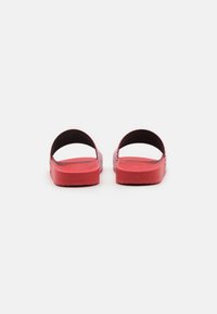 Rode slide-sandalen met een gestructureerde bovenkant, open achterkant en brede banden; platte zolen zonder zichtbare versieringen of logo's.