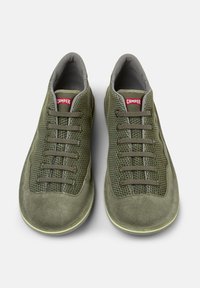 Grüne Wildleder- und Mesh-Schnürschuhe mit einem flachen Design, das graue Akzente und ein rotes Logo oben aufweist.