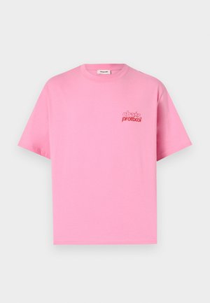 T-shirt rose uni à manches courtes avec un petit texte rouge "cha* protocol" sur la poitrine gauche, présenté sur un fond blanc.