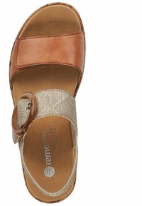 Sandale à glissière en cuir marron avec une sangle dorée texturée dotée d'un accent en bois rond, semelle intérieure rembourrée et semelle extérieure marron à motifs.