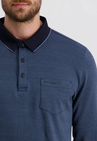 Dunkelblaues Polohemd mit Fischgrätenmuster, kontrastiertem Kragen, drei Knopfverschluss und einer Brusttasche.