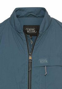 Leichte blaue Jacke mit Stehkragen, einem Frontreißverschluss und einer gebrandeten Tasche. Sie hat eine glatte Textur und kontrastierende schwarze Reißverschlussdetails.