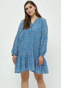 Blau bedrucktes Kleid mit langen Ärmeln, V-Ausschnitt und gestuften Rüschensaum. Es weist ein geometrisches Muster in Blau- und Weißtönen auf.