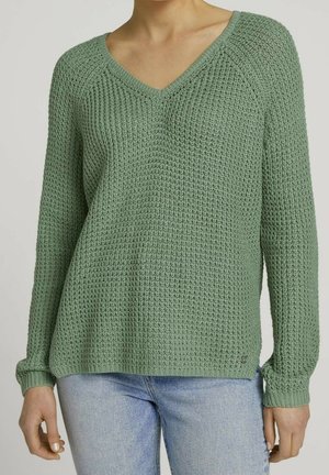 Sweter z dekoltem w serek, z długimi rękawami, wykonany z teksturowanej zielonej dzianiny. Posiada ściągacze na rękawach i u dołu, lekki rozcięcie po bokach oraz małą aplikację logo na dole.