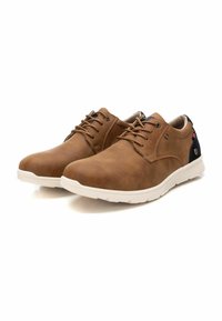 Zapatos de imitación de cuero marrón con punta redondeada, diseño de cordones, suelas de goma blanca y acentos en azul marino en el talón. Superficie texturizada.