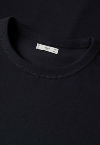 T-shirt en coton noir avec un col rond, une étiquette indiquant la taille M et plusieurs codes pays, et une texture lisse et uniforme.