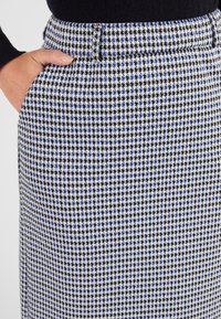 Zwart-wit rok met houndstoothpatroon en blauwe accenten, met een rechte snit, tailleband en zijvakken.