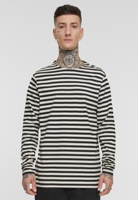 T-shirt à manches longues et col rond, en noir et blanc à rayures horizontales, fabriqué en tissu doux avec une coupe décontractée et de simples détails de couture.
