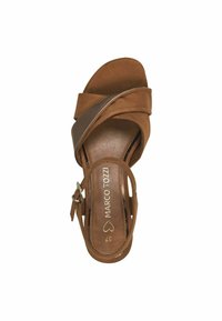 Brown leather sandal with crossed straps, open toe, and ankle buckle. Textured footbed and smooth design, featuring embossed brand logo.