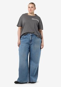 Gray cotton t-shirt with "HOLLYWOOD" print, paired with light blue wide-leg jeans made of denim, featuring a relaxed fit and casual design.