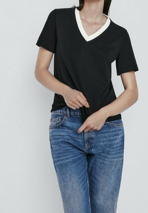 Zwart T-shirt met korte mouwen en V-hals met een crèmekleurige kraag, gecombineerd met lichtblauwe spijkerbroek met een vervaagde textuur en klassieke pasvorm.