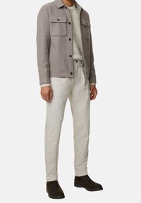 Grå uldblandingsjakke med to brystlommer, cremefarvet struktureret sweater, off-white bukser og mørkebrun ruskinds ankelstøvler.