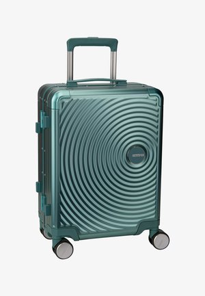 Valise rigide de couleur bleu canard avec un motif circulaire concentrique, poignée rétractable, quatre roues et un logo à l'avant.