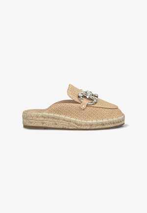 Espadrilla intrecciata beige con una spilla decorativa in argento e dettagli in pelle. Presenta una suola in corda di juta e un design a punta rotonda.