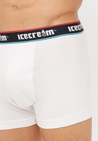 White cotton boxer briefs with a black waistband featuring red and blue accents and "icecream" branding. Soft, fitted design.