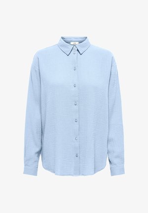 Vaaleansininen pitkähihaisen napitettavan paidan, jossa on teksturoitu kangas ja klassinen kaulus. Paita on hieman löysä ja siinä on kalvosinhiat.