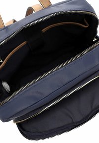 Jūras zilas auduma soma ar brūnām ādas detaļām; satur ar rāvējslēdzēju aizveramu galveno nodalījumu un iekšējās kabatas ar gludu, teksturētu oderi.