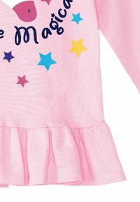 Vaaleanpunainen pitkähihainen paita, jossa on röyhelöhelma, värikkäitä tähtiä ja tummansinisellä teksti "ole maaginen". Pehmeä, puuvillainen materiaali.