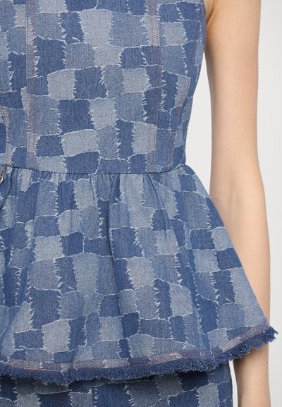 Denim peplum top s modrým a svetlomodrým patchworkovým vzorom, rozstrapkaným lemom a kontrastným oranžovým šitím.