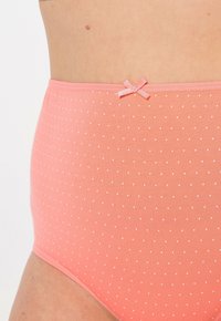Koraalroze highwaisted ondergoed met witte stippen. Heeft een gladde textuur en een klein roze strikje als accent op de tailleband.