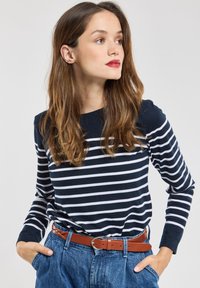 Marineblå og hvide stribede langærmede skjorte parret med høj talje denim jeans og et brunt bælte. Glat bomuldsstof, afslappet pasform.
