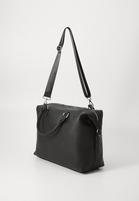 Svart skinn tote bag med en glatt overflate, med doble håndtak og en avtagbar skulderrem, samt vevet tekstur på den ene siden.
