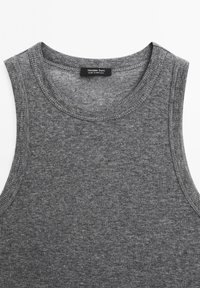 Grå ärmlös linne med rund halsringning och texturerat material. Etiketten visar "Massimo Dutti, Tillverkad i Portugal." Sömmarna är synliga.