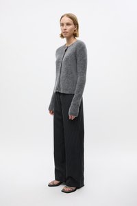 Gray wool cardigan with long sleeves and button front, paired with black pinstriped wide-leg pants and flat sandals. Simple, textured design.