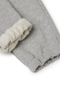 Graue Stoff-Jogginghose mit breitem cremefarbigen Strickbund. Weiche Textur, lässige Passform, elastischer Bund und Bündchen verleihen einen bequemen, entspannten Look.