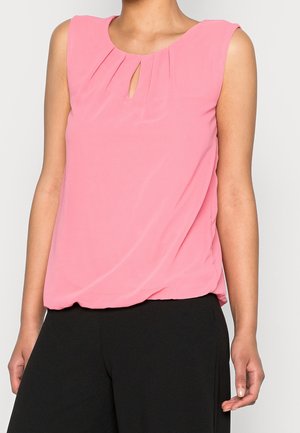 Blouse sans manches rose avec un détail en trou de serrure, design à devant plissé, tissu léger et coupe décontractée, associée à un bas noir.
