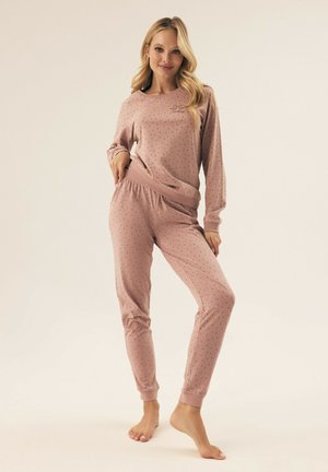 Pink polka dot pajama set in soft fabric, featuring a long-sleeve top and tapered pants with cuffs and an elastic waistband.