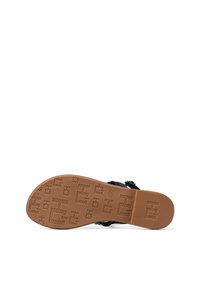 Sandal nero con suola in gomma marrone testurizzata. Presenta un motivo impresso, cinturini regolabili e un design piatto.