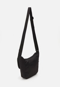 Borsa a spalla nera in nylon con una lunga tracolla regolabile e una tasca frontale con zip. Texture liscia, forma rettangolare semplice.