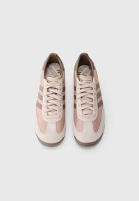 Růžové semišové a síťovinové tenisky se třemi hnědými pruhy, šněrováním, gumovou podrážkou a stélkou s logovým vzorem.