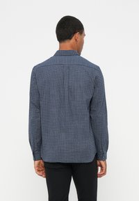 Camicia a quadri blu navy con maniche lunghe, colletto button-down e dettaglio sulla parte posteriore, realizzata in tessuto a trama con una consistenza morbida.