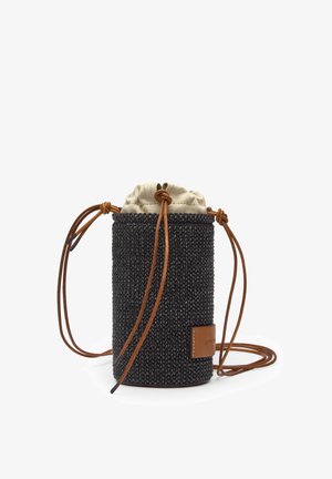 Borsa cilindrica nera intrecciata con parte superiore in tessuto beige con coulisse, tracolla in pelle marrone e patch logo su sfondo bianco.