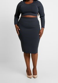 Modro-olivově zelený dvoudílný pruhovaný oblek s krátkým topem s dlouhými rukávy a sukní po kolena, vyrobený z měkké elastické látky.