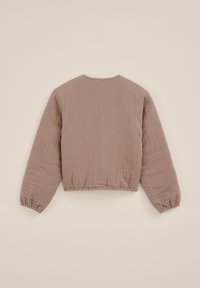 Jachetă cu mâneci lungi, de culoare maronie deschis, texturată, cu manșete elastice și talie elastică, văzută din spate pe un fond simplu bej.