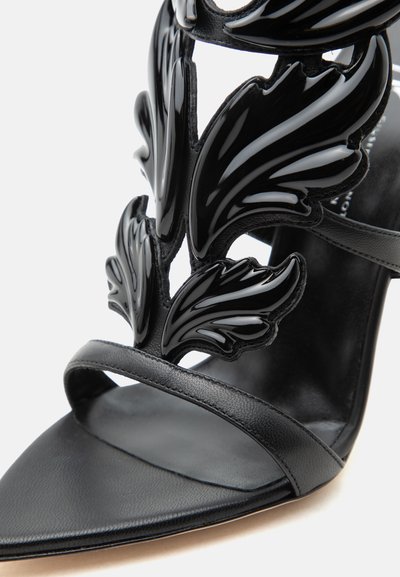 Μαύρο πέδιλο με ψηλό τακούνι, με γυαλιστερές διακοσμήσεις σε σχήμα φύλλων και λεπτό λουράκι πάνω από τα δάχτυλα.