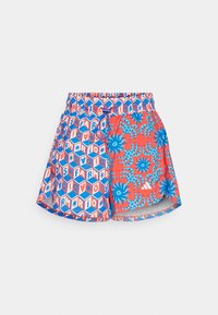 Värikaskylpytakki, jossa on geometrinen kuusikulmainen kuvio sinisessä ja punaisessa, trooppisilla kukkakoristeilla, joustava vyötärö ja sivutaskut.